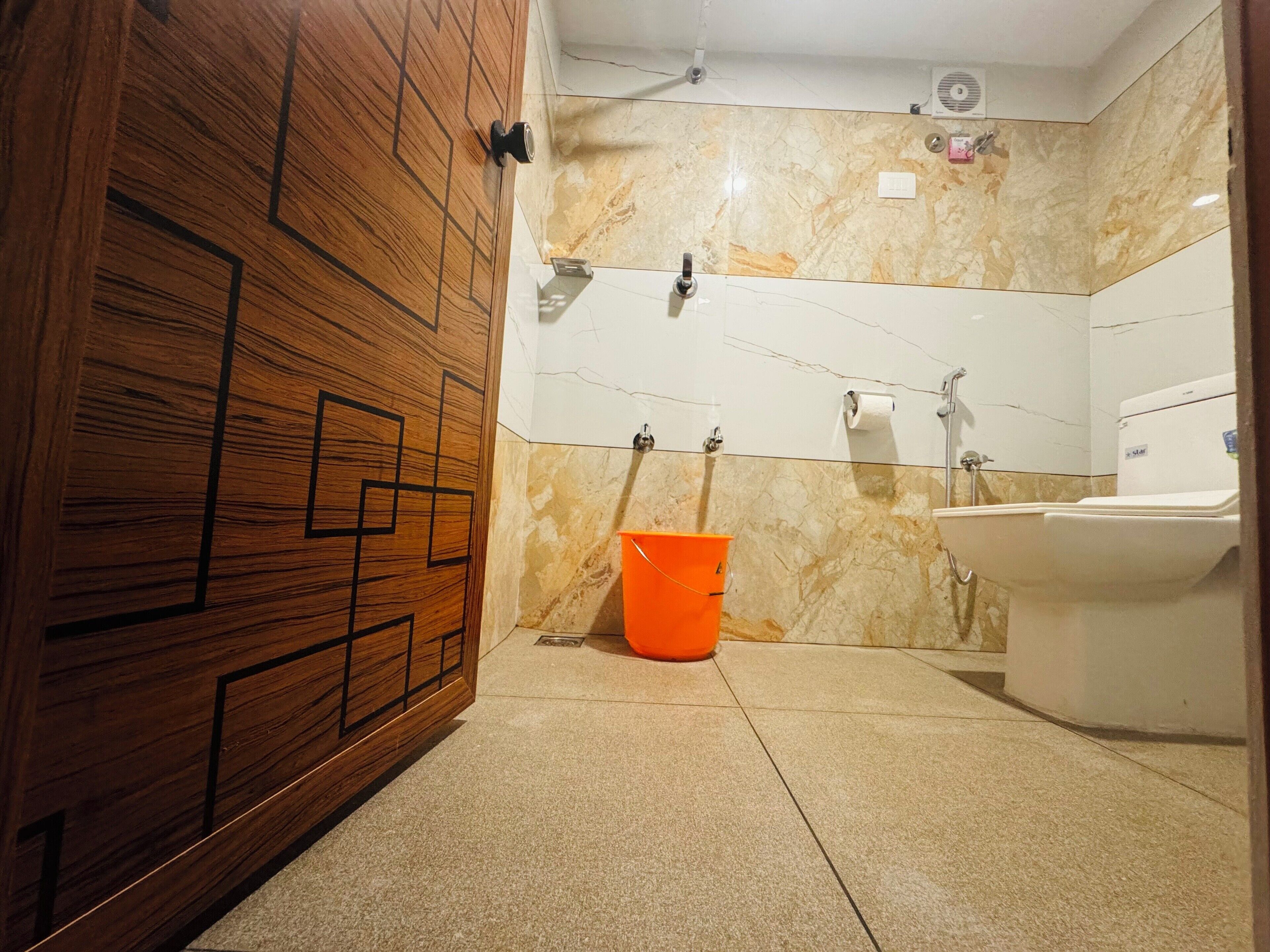 A bathroom with a wooden door, a sink, a toilet, and a shower.