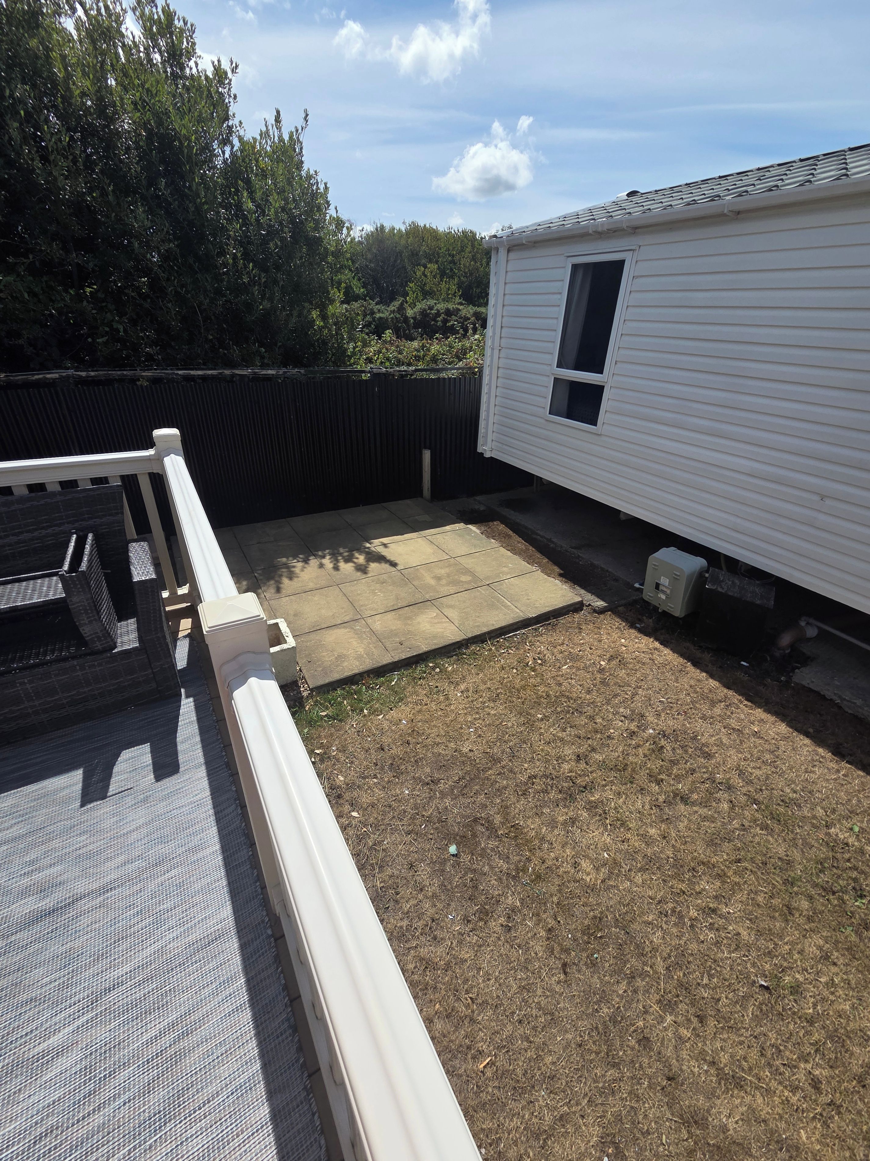 A residential area with a white mobile home, a fenced yard, and a patio area.