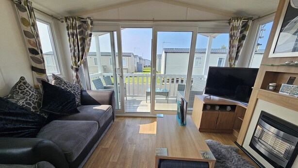 Ein Wohnzimmer mit einer Couch, einem Fernseher, einem Kamin und Blick ins Freie.