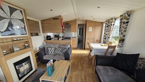 Ein modernes Wohnzimmer mit Kamin, einer Couch, einem Couchtisch und einem Essbereich mit Tisch und Stühlen.