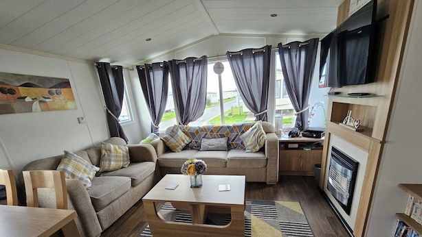 A cozy living room with a sofa, coffee table, and a fireplace. - Heidi 2 Bed Robin Hood (Rhyl)