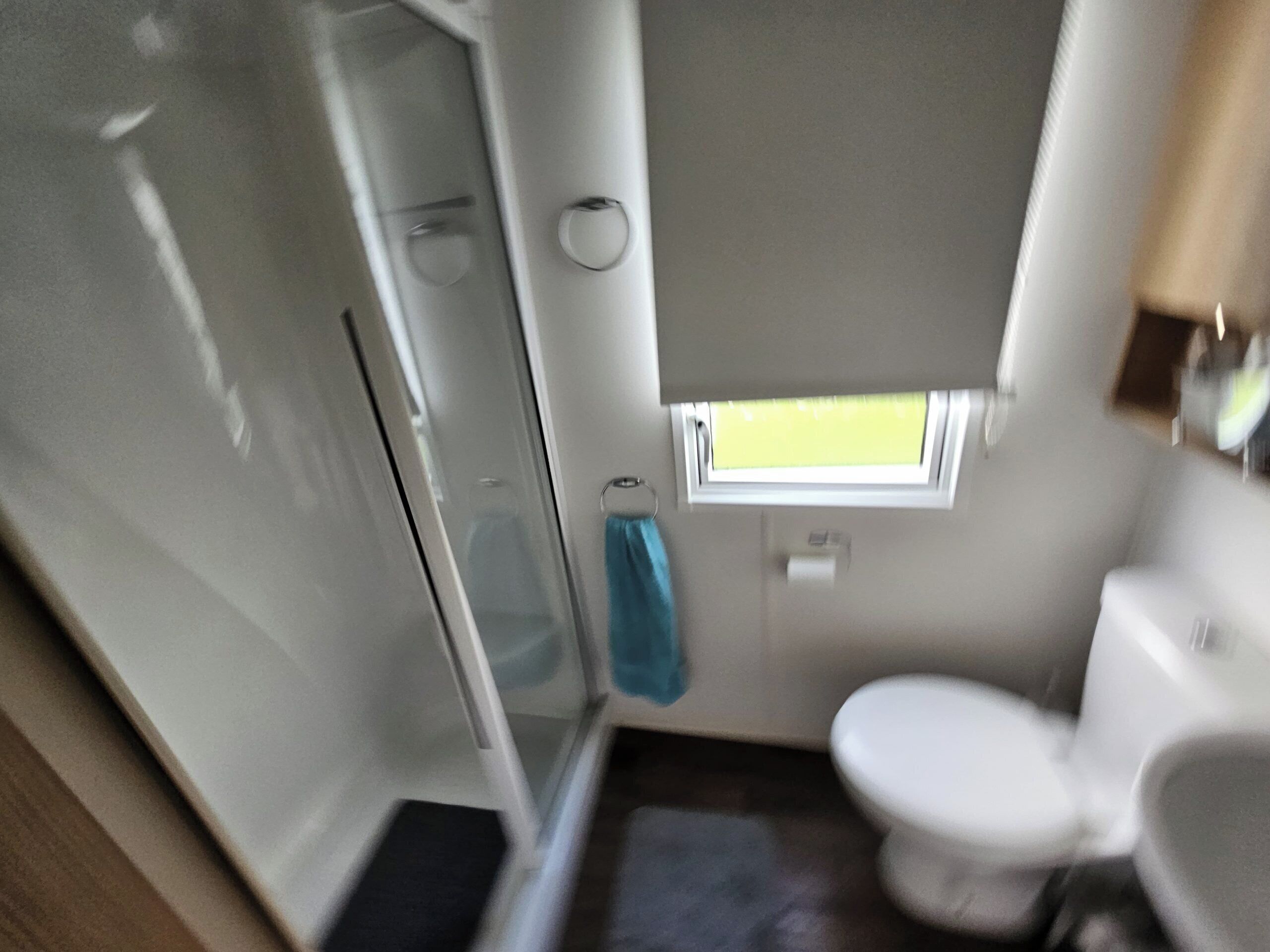 Un bagno compatto con doccia, wc e una piccola finestra.