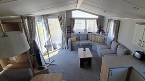 Ein kompaktes Wohnmobil-Interieur mit einer Sitzecke, einem kleinen Tisch, einer Küchenzeile und Vorhängen.