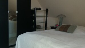 Una camera da letto moderna con un letto grande, un armadio, un comodino e uno specchio.