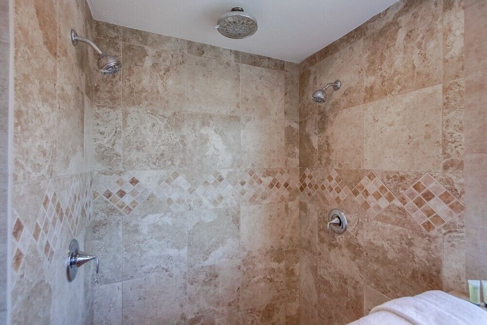 Een douche met een handdouche en een douchekop aan de muur.