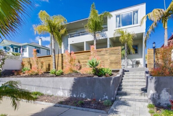 A modern two-story house with a concrete staircase leading to a wooden deck. - Beryl Retreat (San Diego)