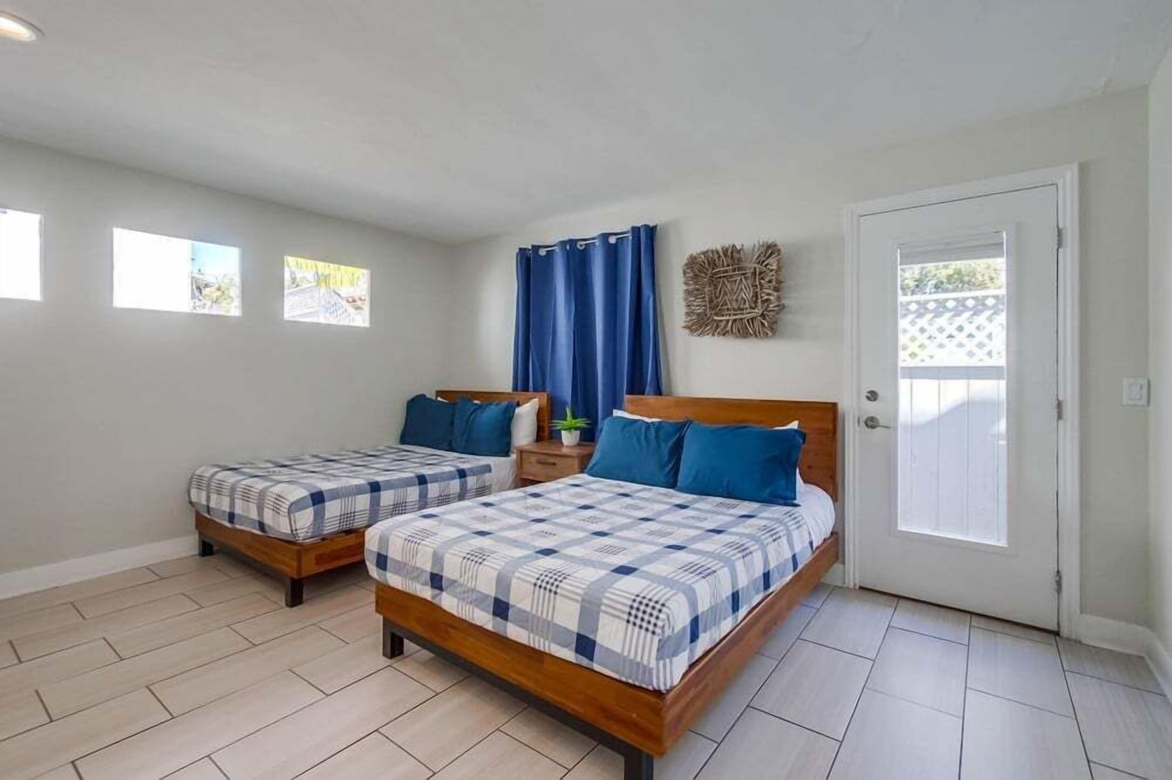 A room with two wooden beds, a white door, and a small window.