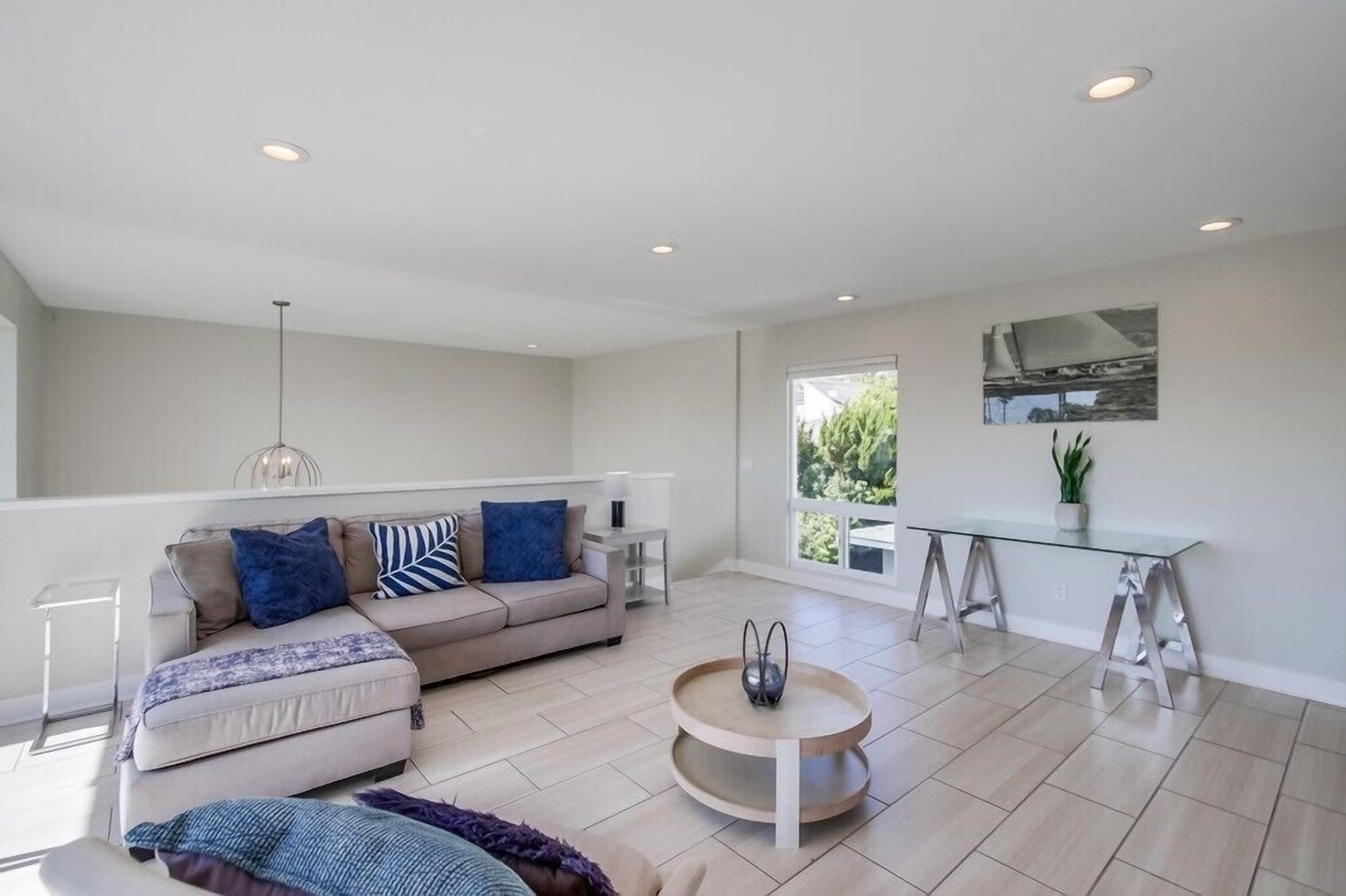 A spacious living area with a sofa, coffee table, and a glass-top dining table.