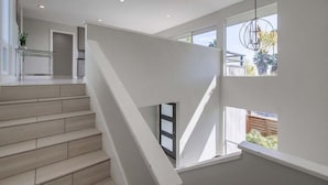 A modern staircase with a glass table and a hanging light fixture. - Beryl Retreat (San Diego)