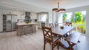 A modern kitchen with a central island, bar stools, and a dining table with chairs. - Beryl Retreat (San Diego)