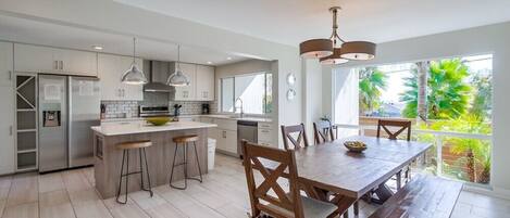 A modern kitchen with a central island, bar stools, and a dining table with chairs.