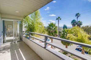 A balcony with a concrete floor, a glass door leading inside, and a view of palm trees and a road. - Beryl Retreat (San Diego)