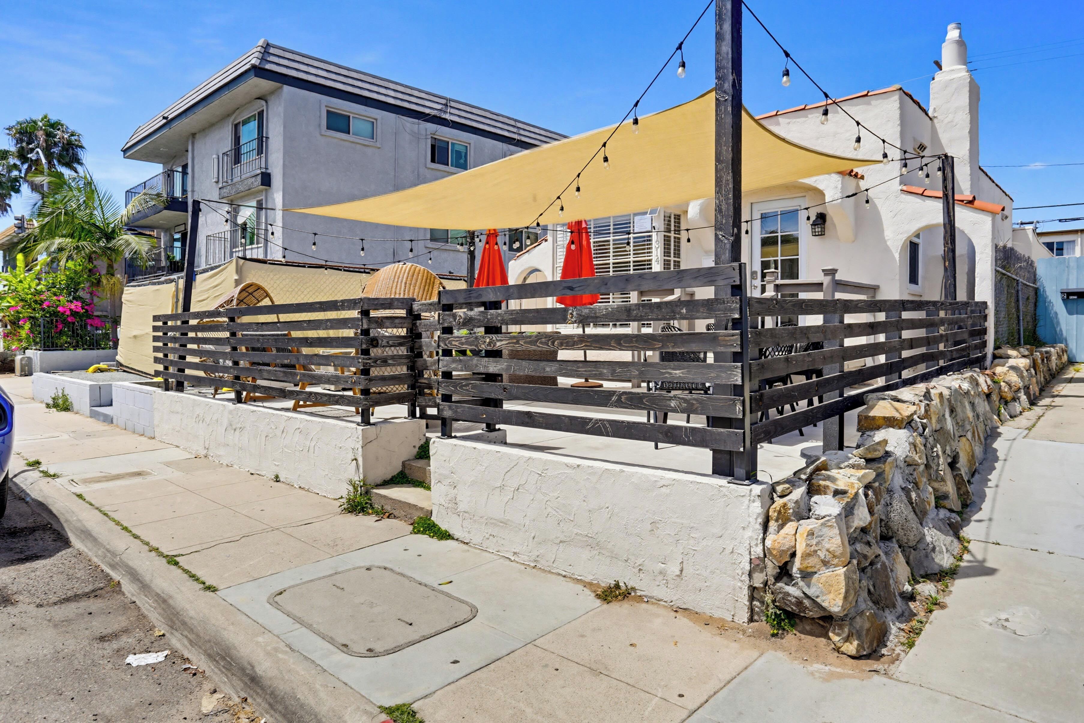 A coastal building with a balcony, outdoor seating, and a stone wall.