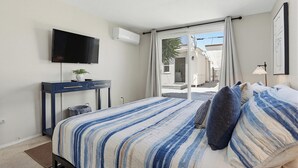 Een slaapkamer met een bed, een bureau, een televisie en uitzicht op het omliggende landschap.