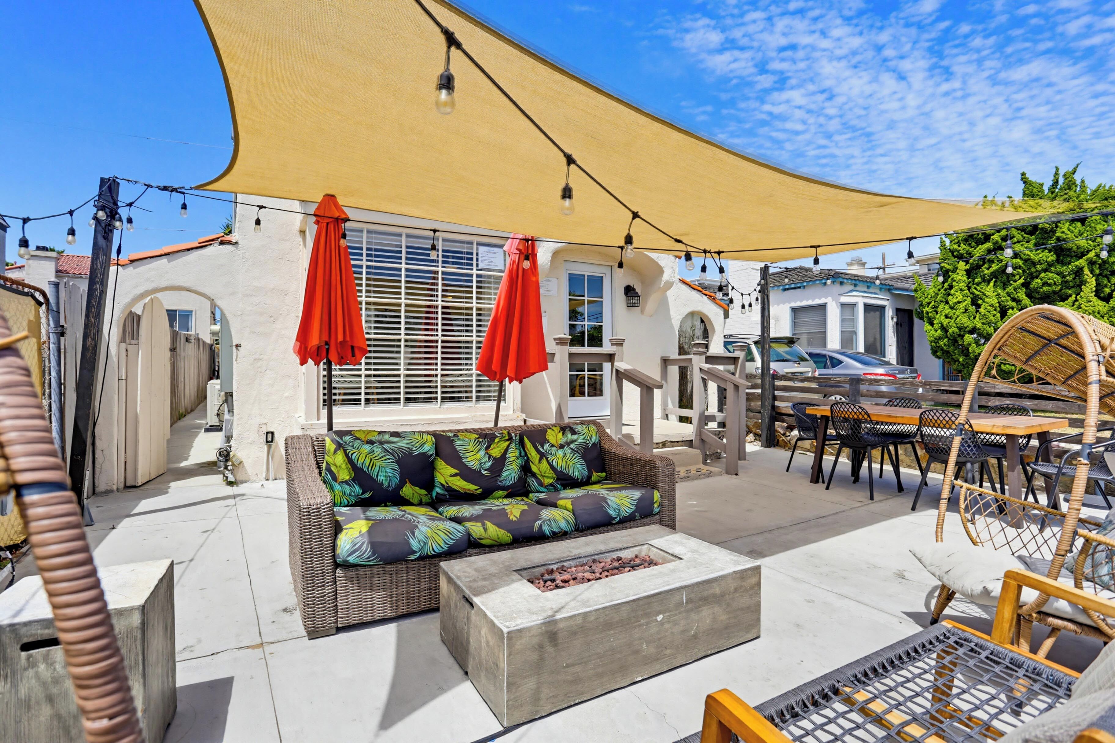 An outdoor patio area with a sofa, chairs, a table, and a fire pit.
