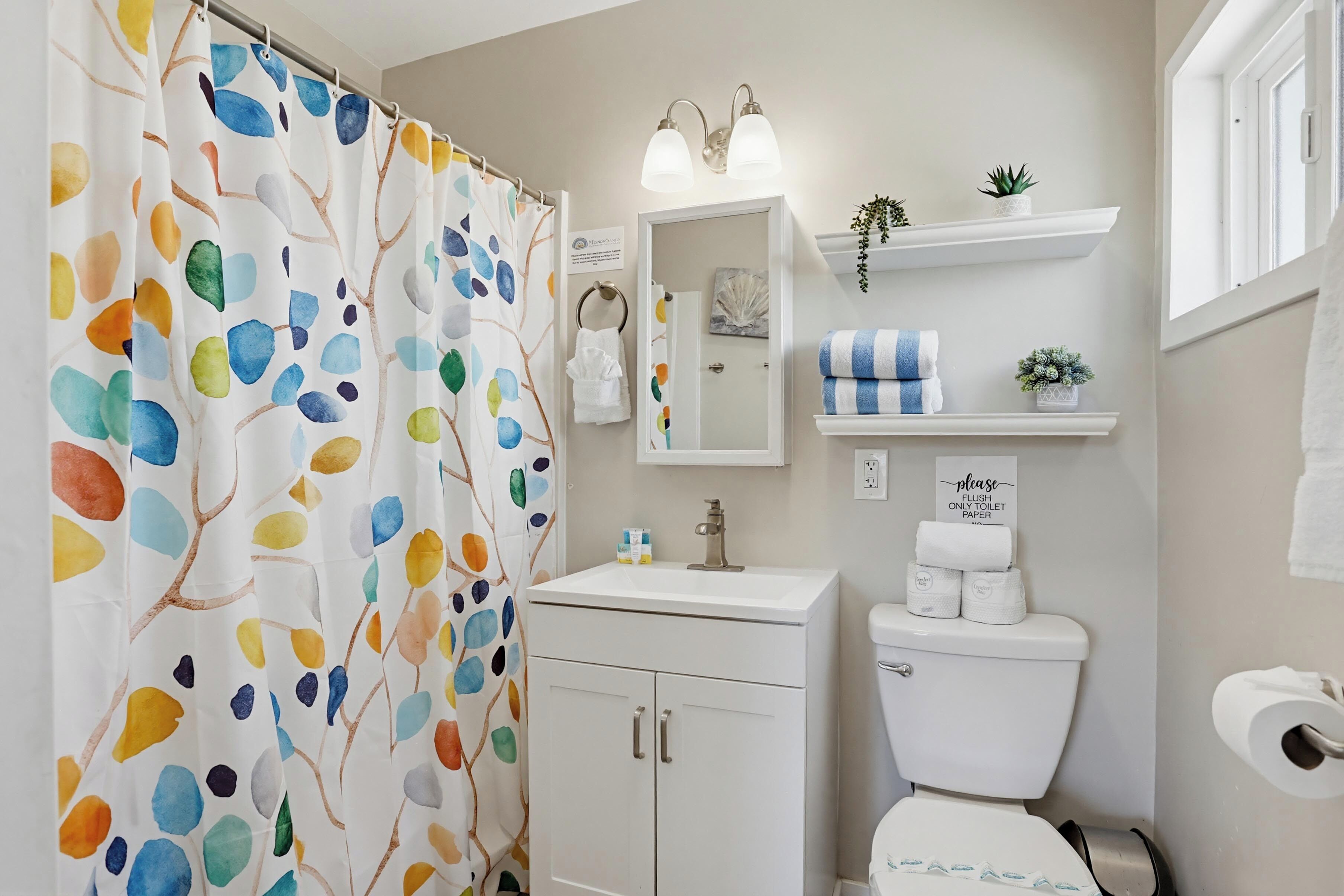 Une salle de bain avec un rideau de douche, un lavabo, des toilettes et un miroir.