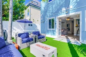 A modern outdoor living area with a white coffee table, blue cushioned seating, and a patio umbrella. - Casa Azul (San Diego)