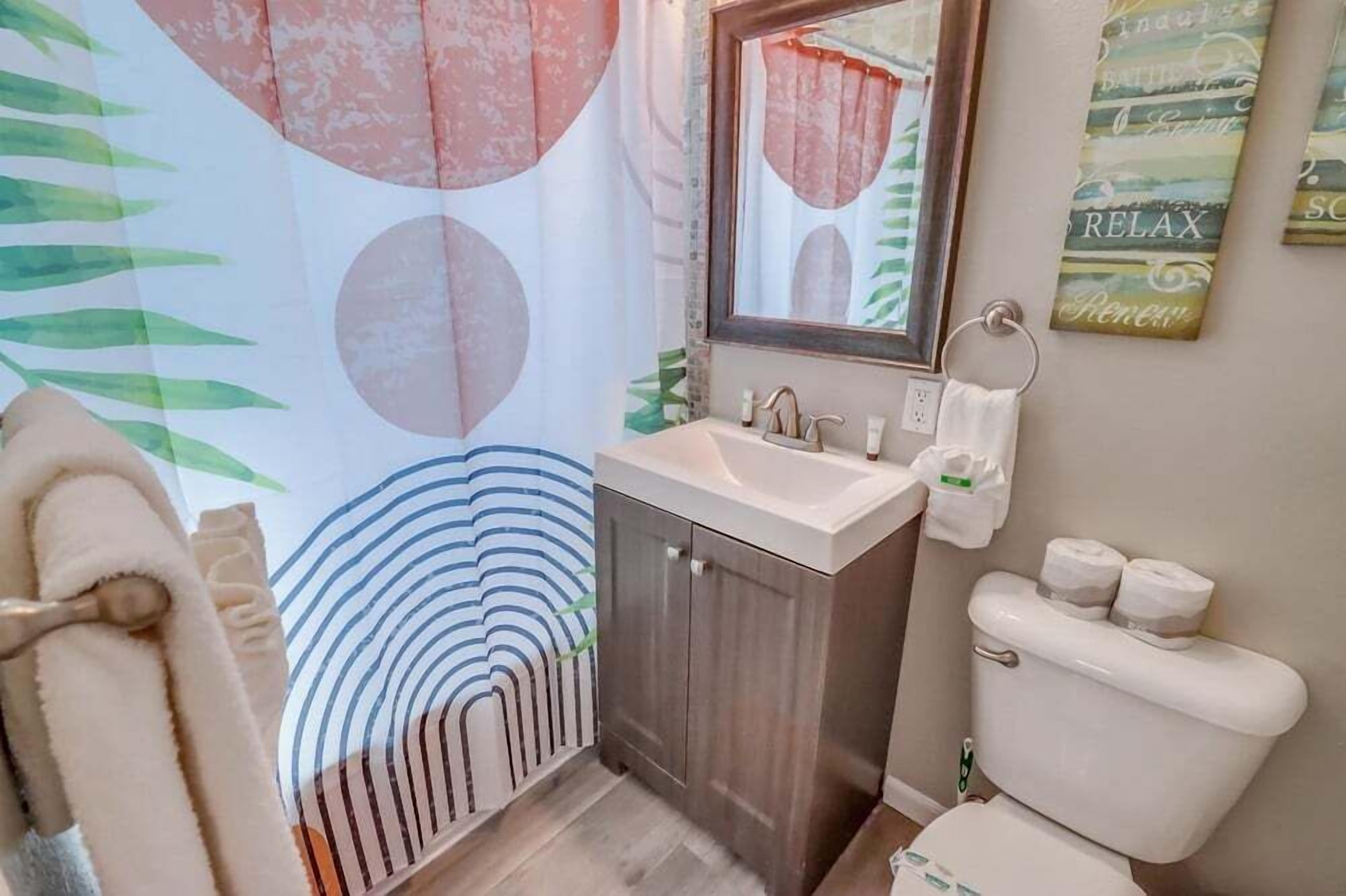 Een badkamer met een wastafel, spiegel, toilet en handdoekhouder.