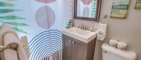 Een badkamer met een wastafel, spiegel, toilet en handdoekhouder.