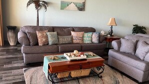 A living room with a sofa, a coffee table with decorative items, a lamp, and a painting on the wall. - Southern Comfort at the Sonoran Sun (Puerto Peñasco)