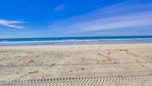 Une plage de sable où l’on peut voir des empreintes menant à l’eau.