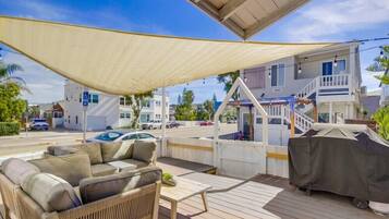 Relax on the shaded deck with a sofa and wicker chair, perfect for dining or unwinding.