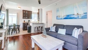 Ein modernes Wohnzimmer mit einem grauen Sofa, einem weißen Couchtisch und einem Bild von Segelbooten an der Wand.