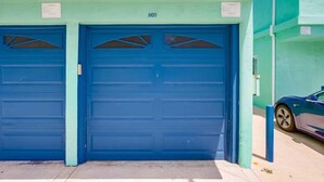 Ein Gebäude mit zwei blauen Garagentoren, beschriftet mit der Nummer 805, und einem parkenden Auto auf der rechten Seite.