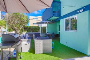 An outdoor patio with a grill, wicker furniture, and a small table. - Manhattan Shores 2 (San Diego)
