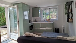 Una cocina compacta con puerta corredera a un balcón, una pequeña zona de comedor y una ventana con vistas a zonas verdes.