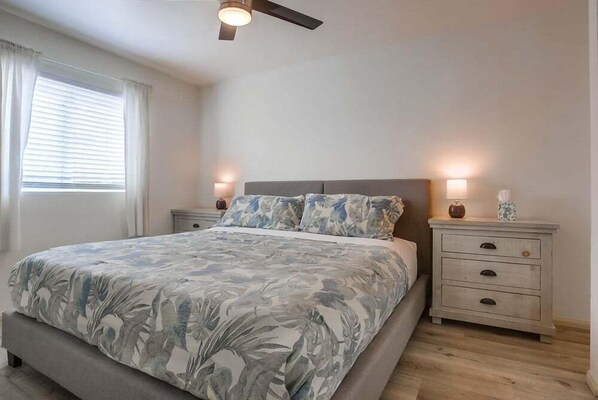 Ein Schlafzimmer mit einem Bett, Nachttischen und einem Deckenventilator.