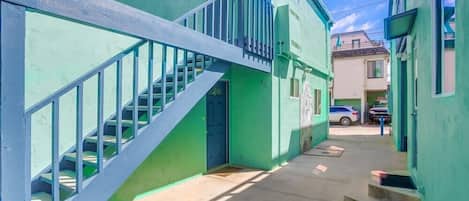 A narrow alleyway with a blue staircase leading to a green building.