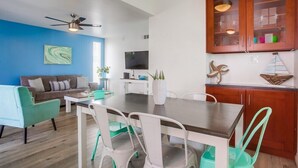 Una sala de estar moderna con una mesa de comedor, sillas, un sofá y un televisor.
