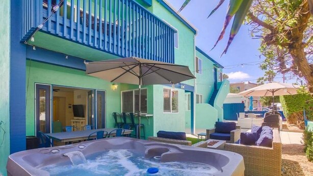 Un jacuzzi en un patio trasero con zona de estar y mobiliario exterior.