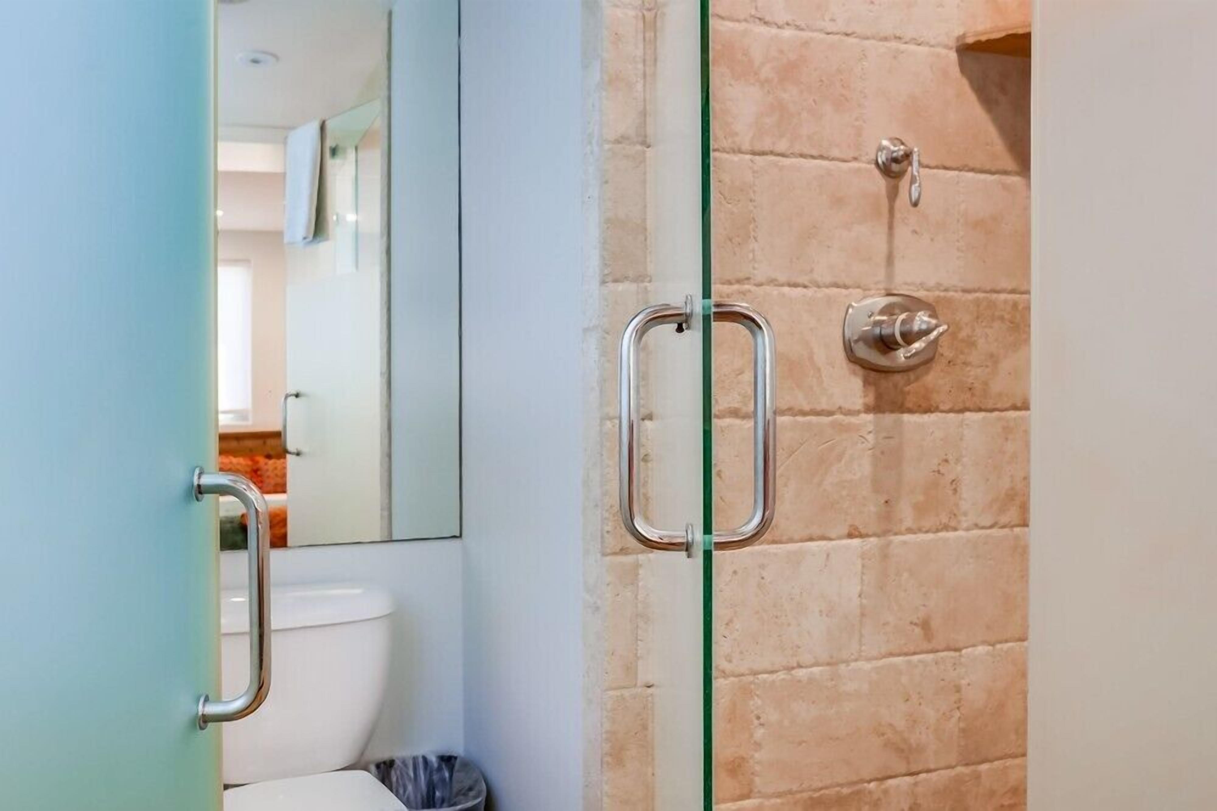 Un bagno con pareti divisorie in vetro, un water, un cestino e una doccia con porta in vetro.