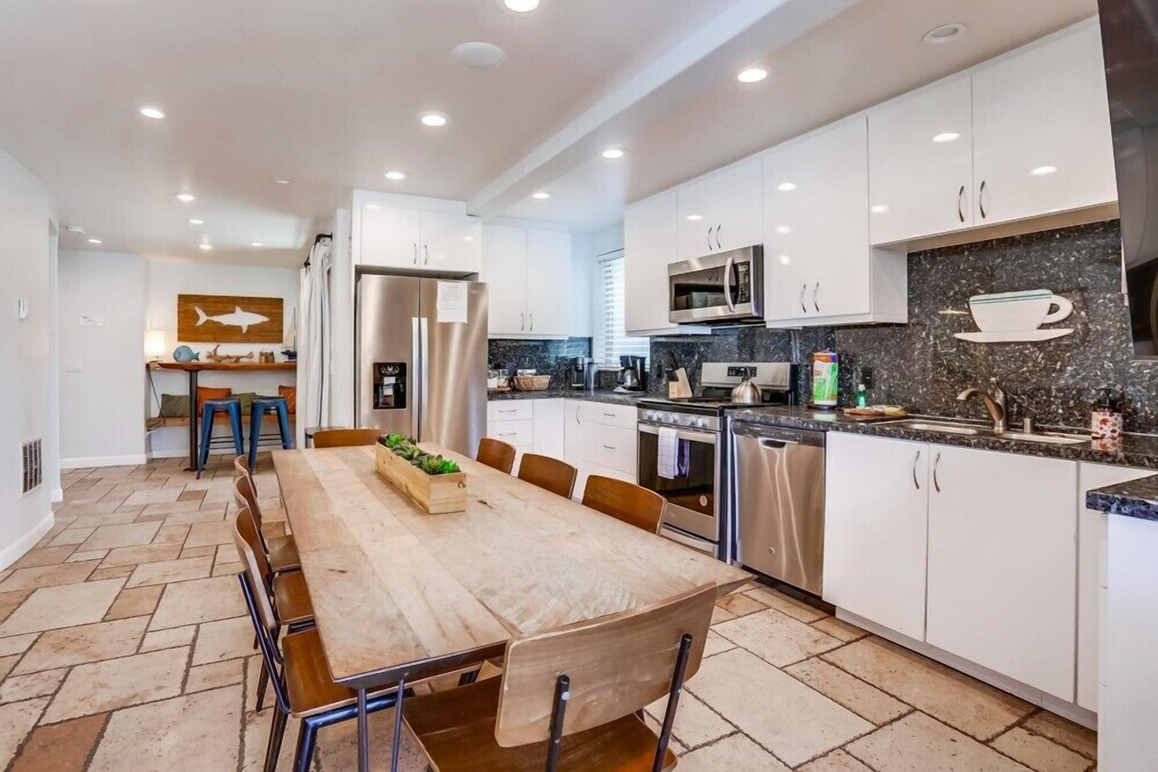 A modern kitchen with white cabinets, stainless steel appliances, and a herringbone tile floor.