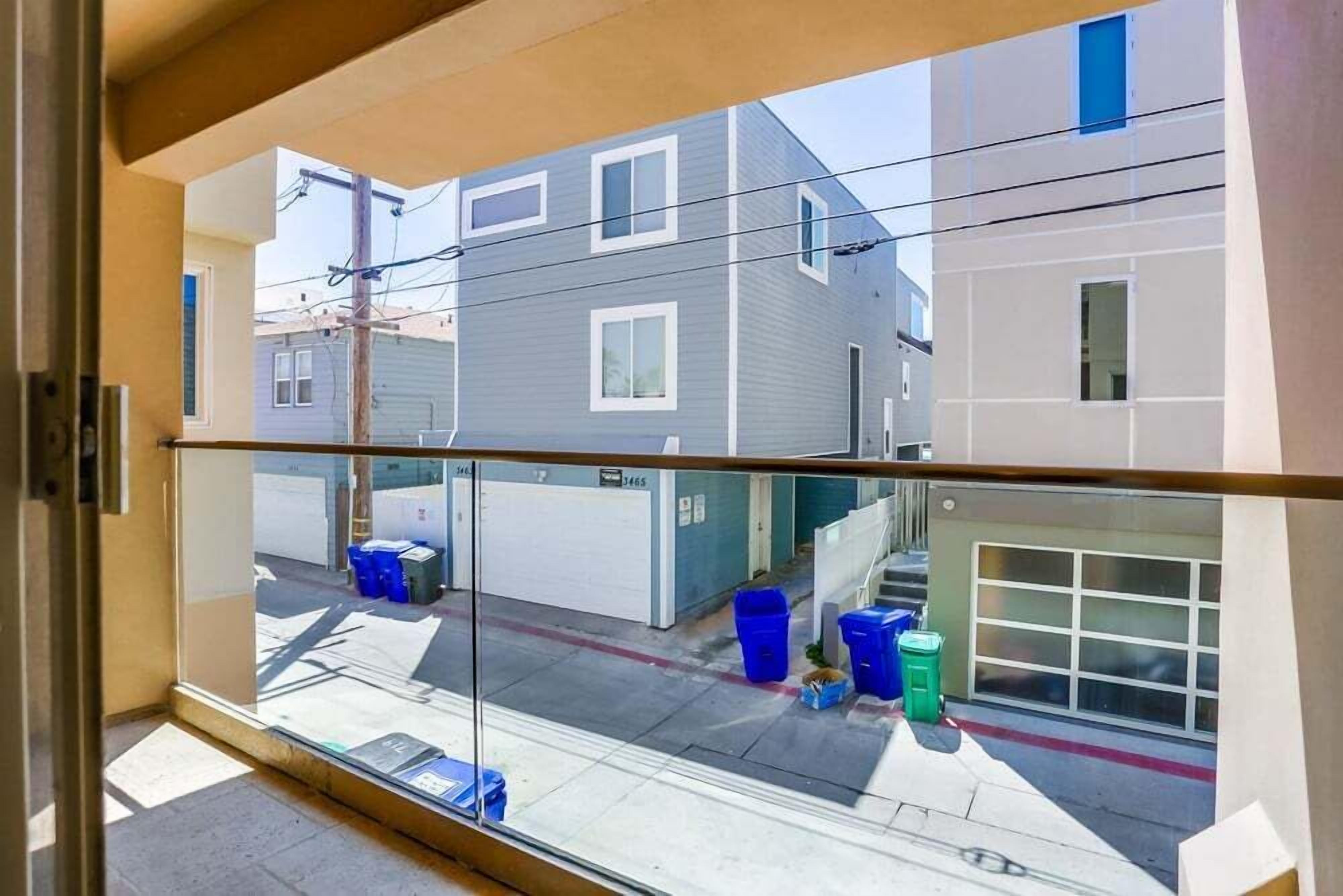 Vista da un interno che si affaccia su una strada con edifici residenziali e un basculante.