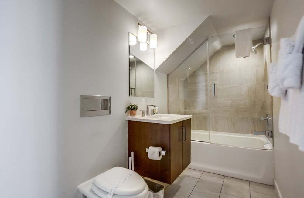 Ein modernes Badezimmer mit einer Glaskabine zur Dusche, einem Holzbadezimmerwaschtisch und einer Toilette.