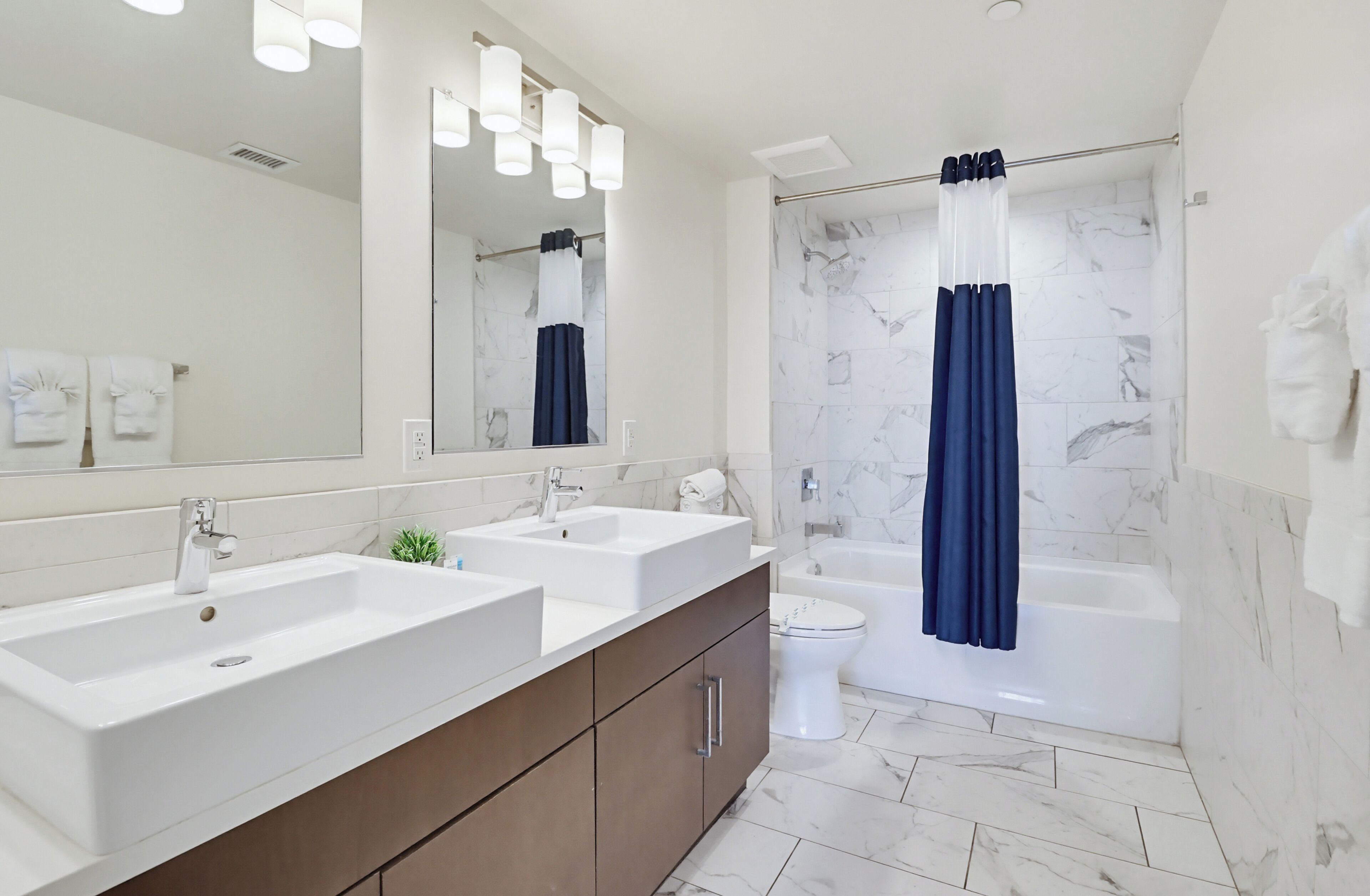 A bathroom with a double sink vanity, a toilet, a bathtub, and a shower curtain.