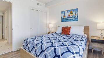 Un dormitorio con cama, mesita de noche, un cuadro y una puerta.