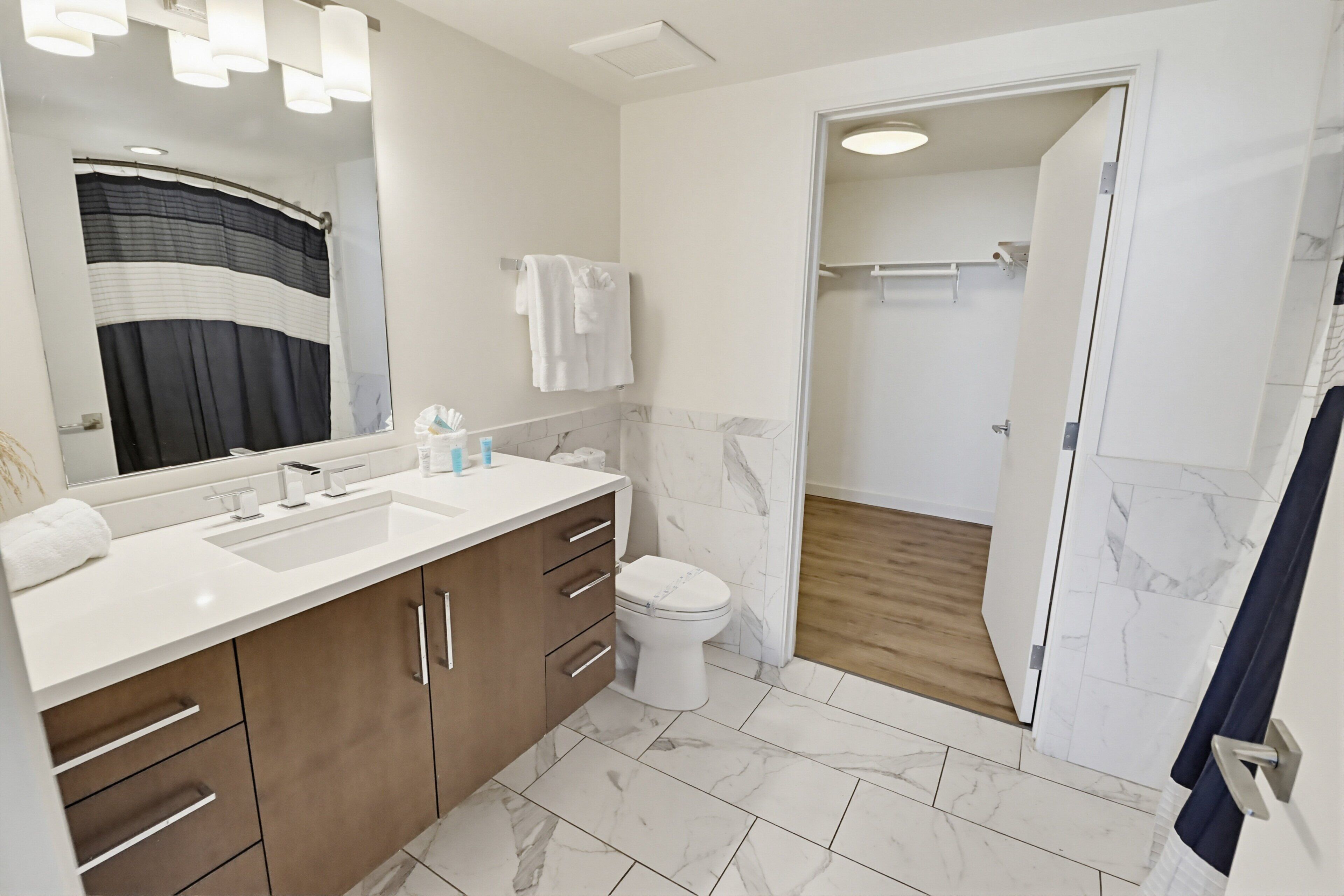 A modern bathroom with a large mirror, a sink, a toilet, and a shower area.