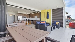 An outdoor patio area with a dining table, sofas, and a kitchen in the background. - Ocean Park 04 (San Diego)