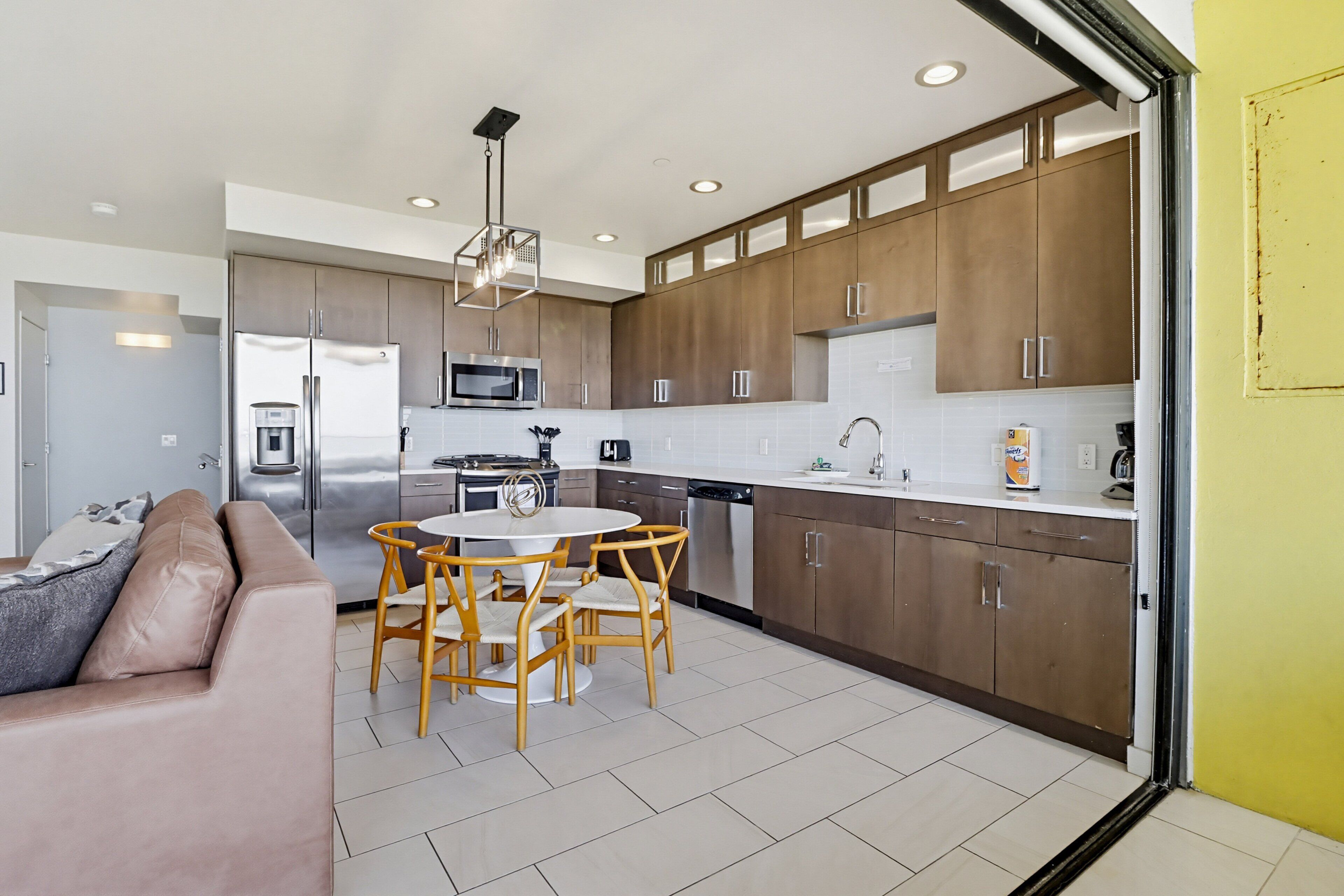 A modern kitchen with a dining area, stainless steel appliances, and wooden cabinets.