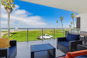 A balcony with outdoor furniture, a view of the beach, and palm trees. - Ocean Park 04 (San Diego)