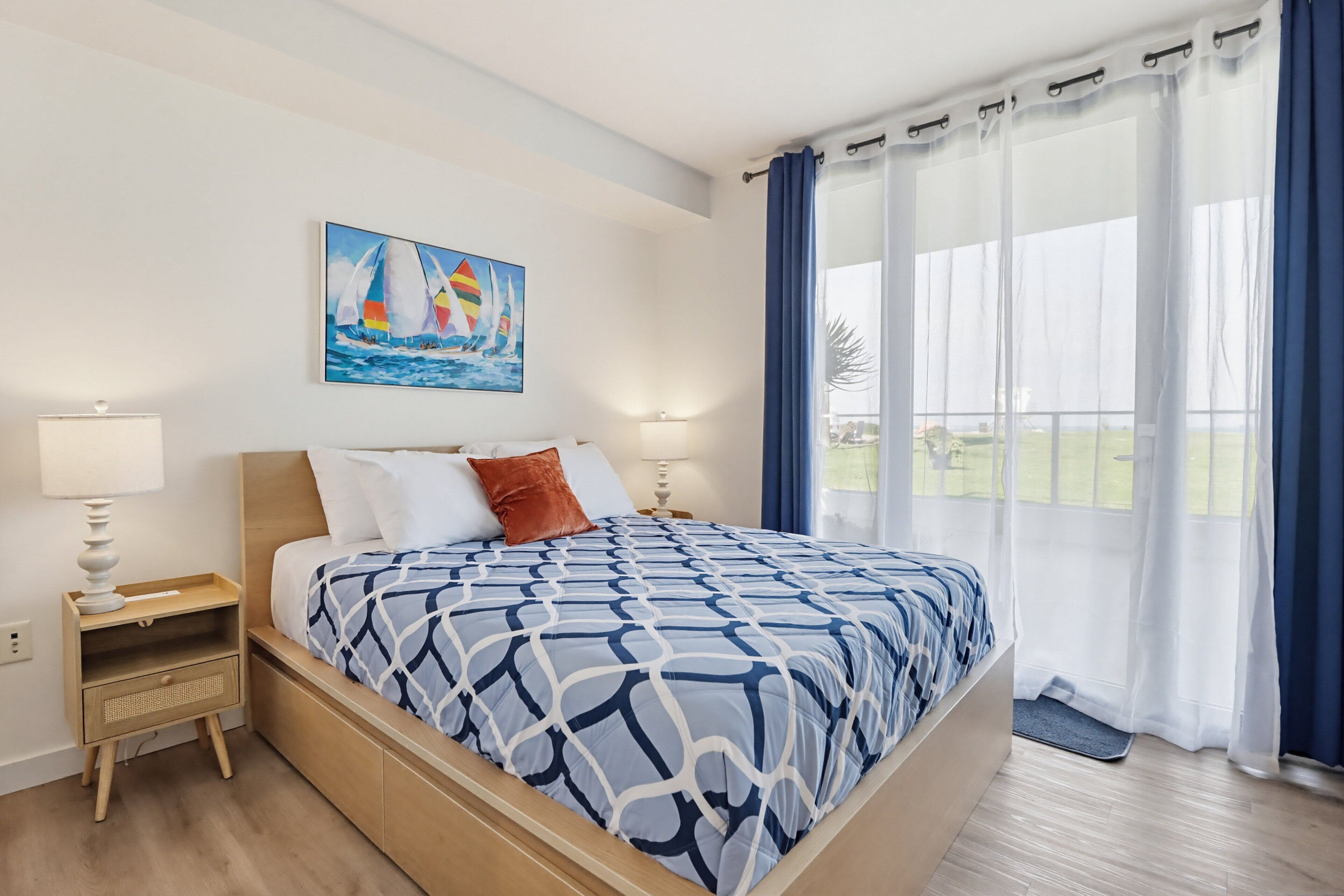 Un dormitorio con una cama, dos mesitas de noche, un cuadro y vistas por la ventana.