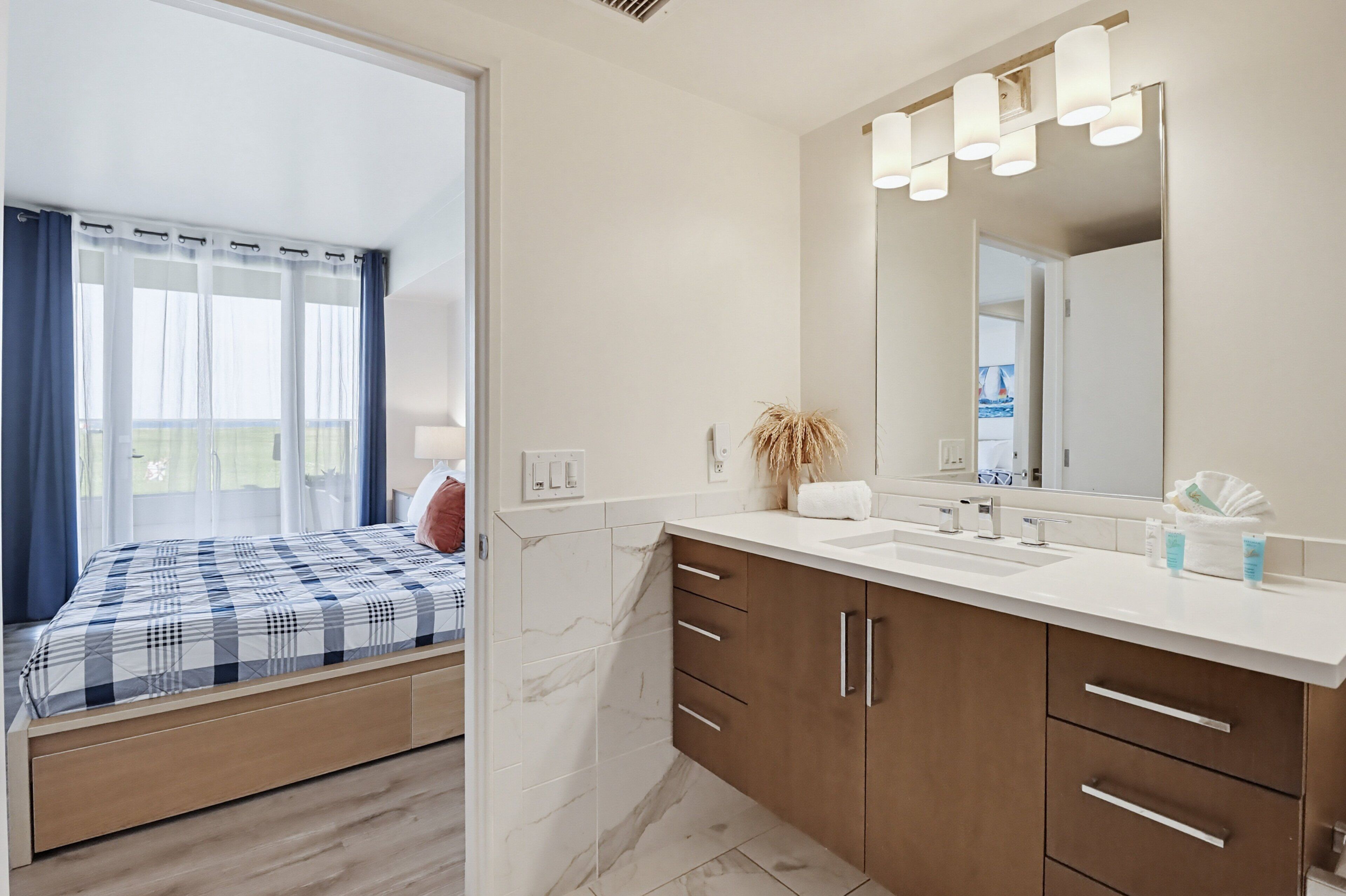 Una habitación de hotel moderna con una cama, un baño con un espejo grande y vistas al exterior.