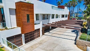 A modern building with a white facade and wooden accents, featuring a covered outdoor area with steps leading to a covered parking space. - Ocean Park 04 (San Diego)