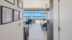 A modern hotel room with a balcony, framed certificates on the wall, and a view of the sea. - Ocean Park 05 (San Diego)