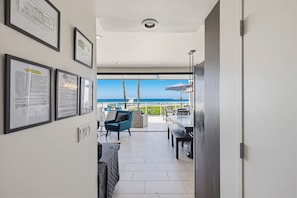 Una habitación de hotel moderna con balcón, certificados enmarcados en la pared y vistas al mar.