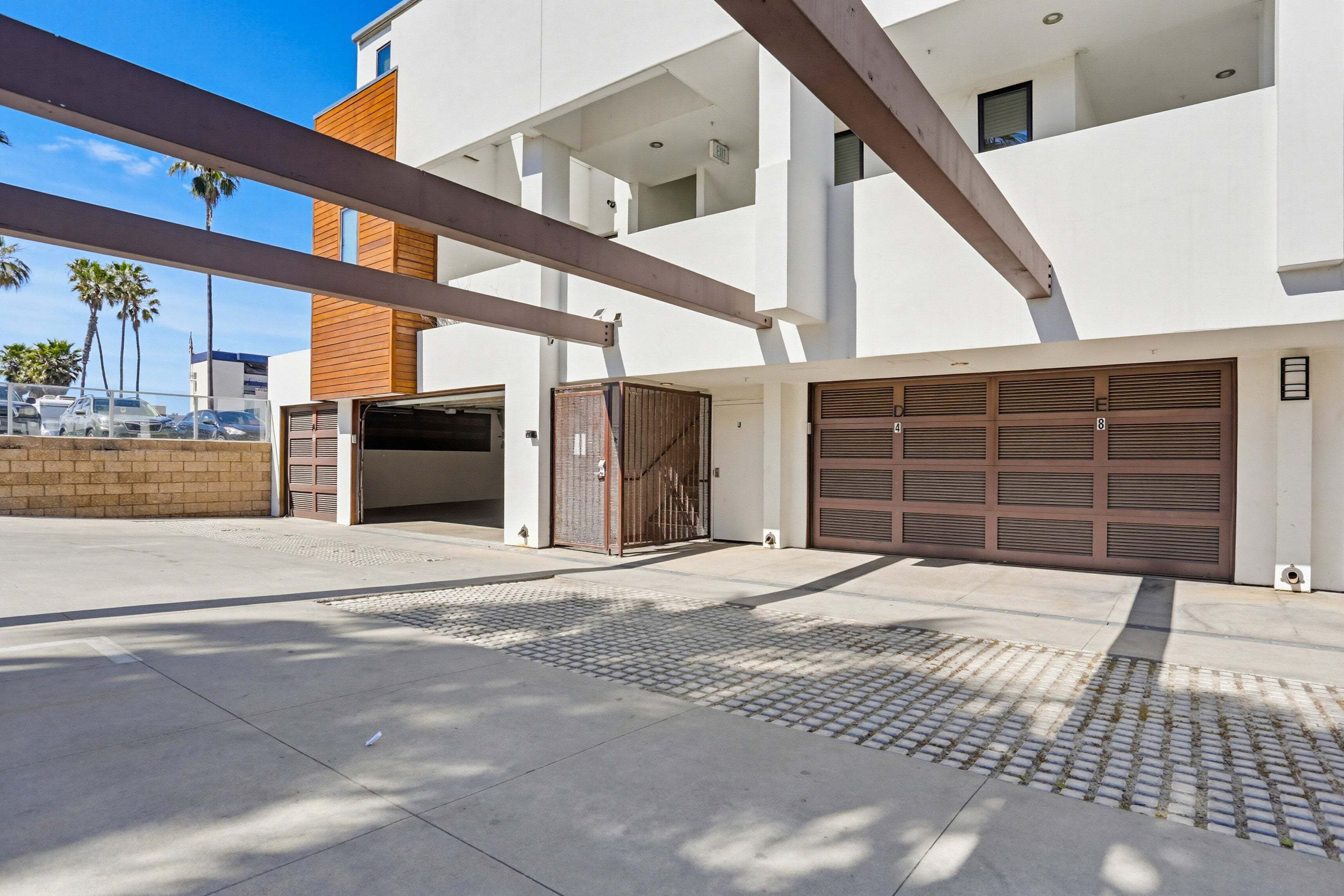 A modern building with a garage, a covered walkway, and a brick wall.